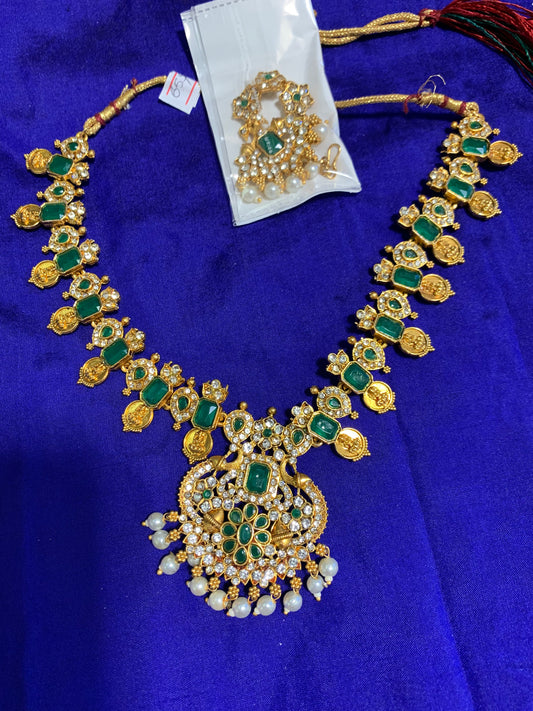 Long golden necklace with green stone